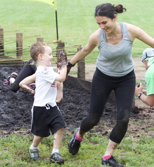 A woman having fun with kids during a mud run