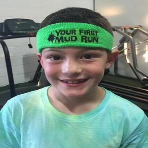 A young boy smiling and wearing a head band