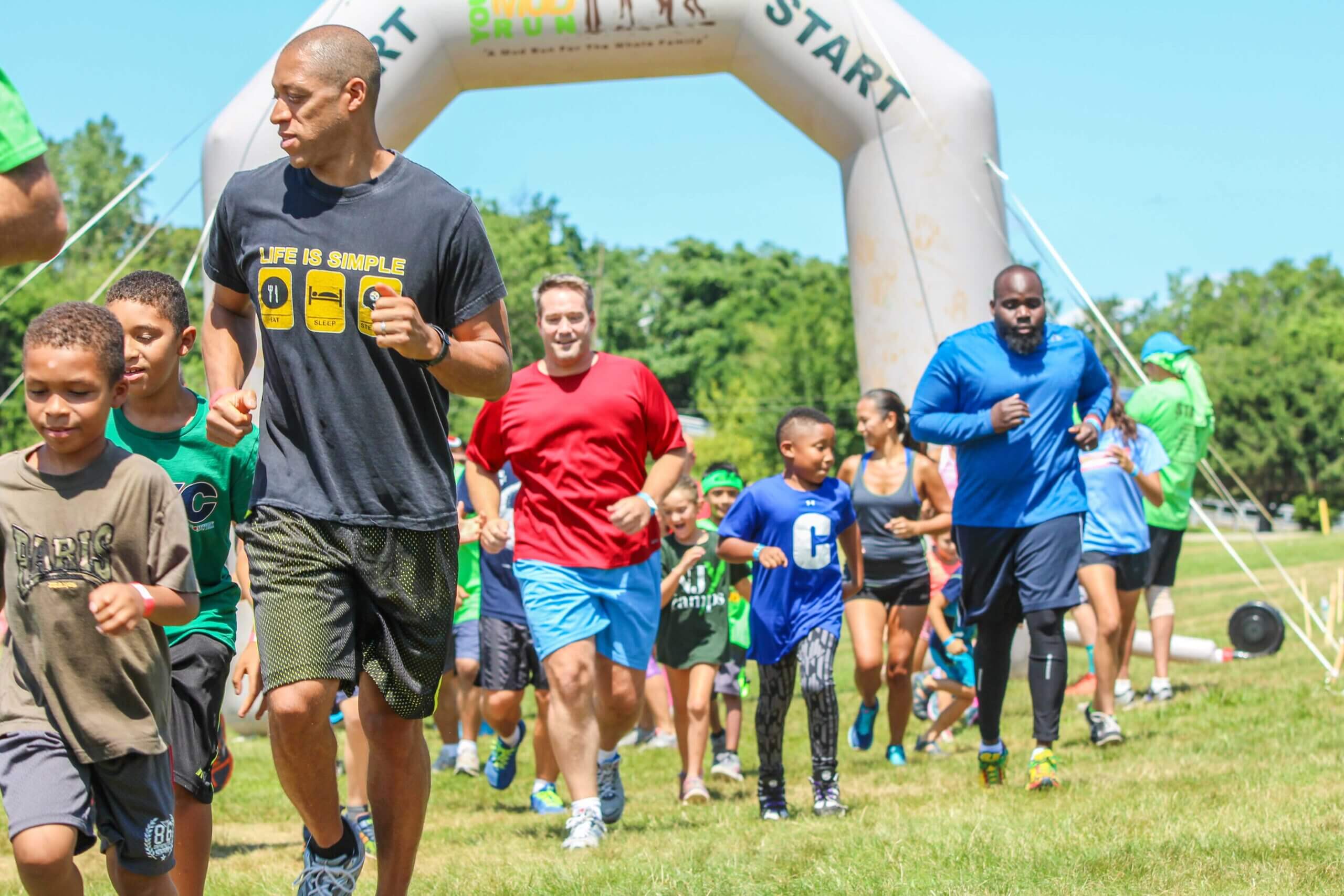 Three adults and kids running on the ground